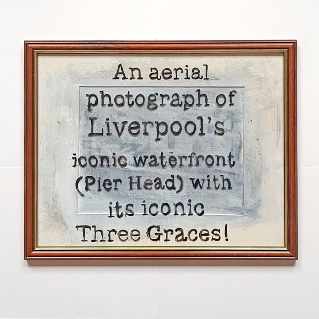 a picture frame with no picture in it with text painted across it saying "an aerial photogragh of Liverpool's iconic waterfront (Pier Head) with iconic Three Graces!"