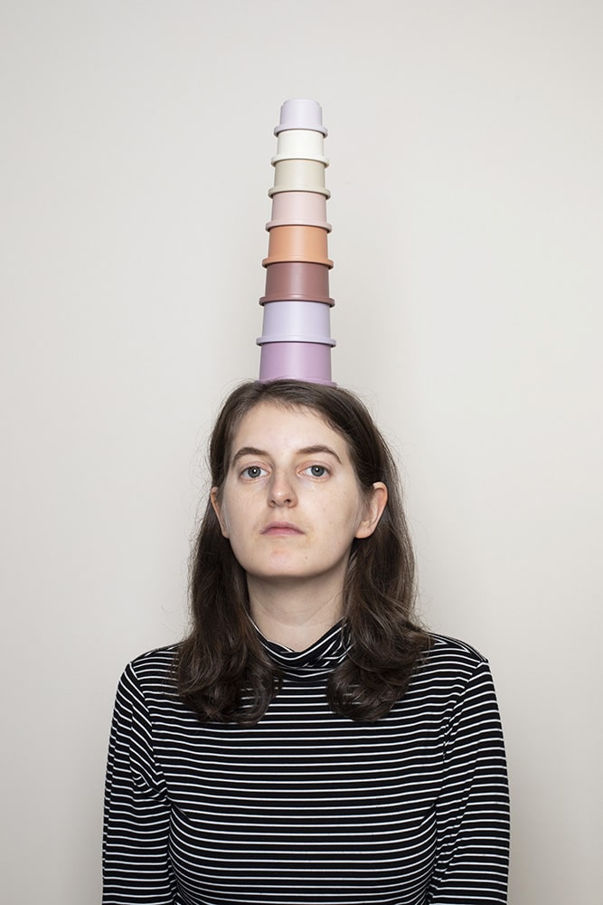 Photograph of a women with children's toy pots balancing on her head