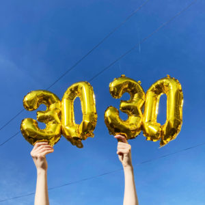 Balloons in the shape of the number 30, held up against a blue sky