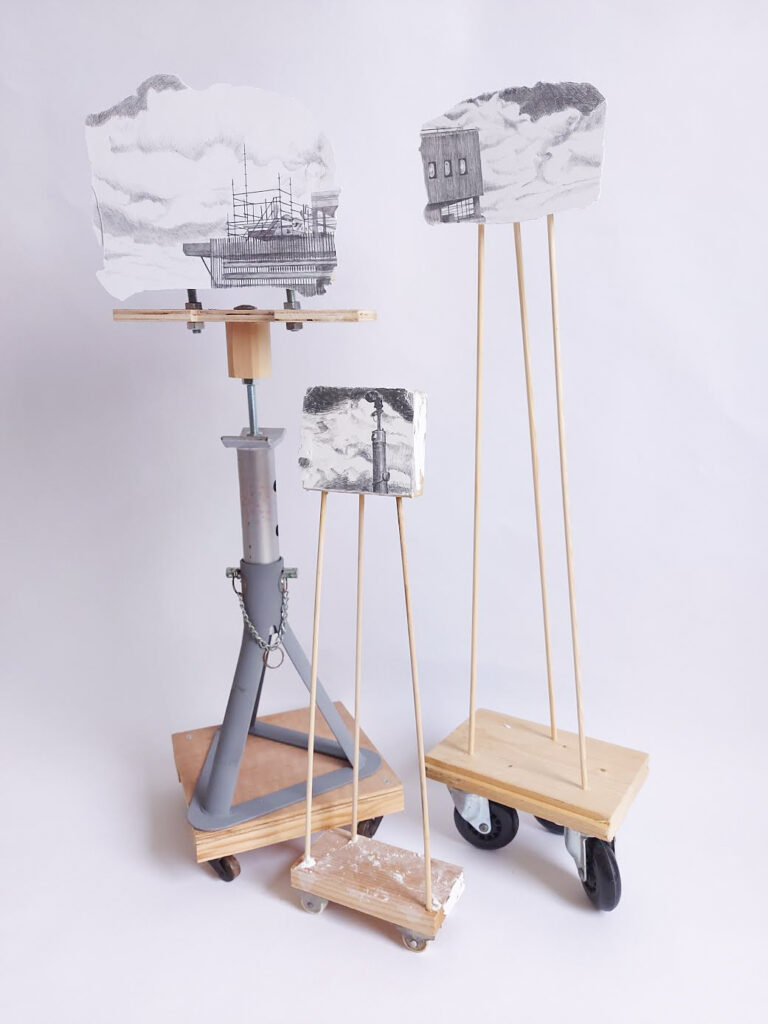 a photograph of three drawings made on plaster that are mounted on stands made from wood and metal that are on wheels