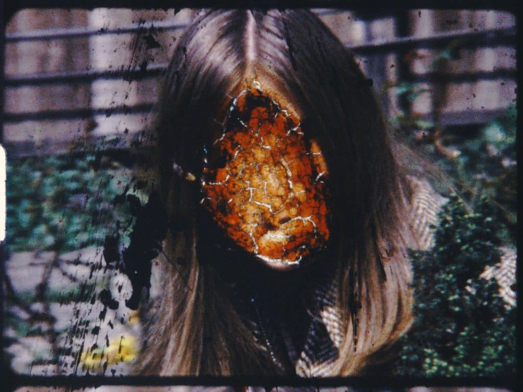 a photograph of a film being projected. The film still is of a women with the face removed