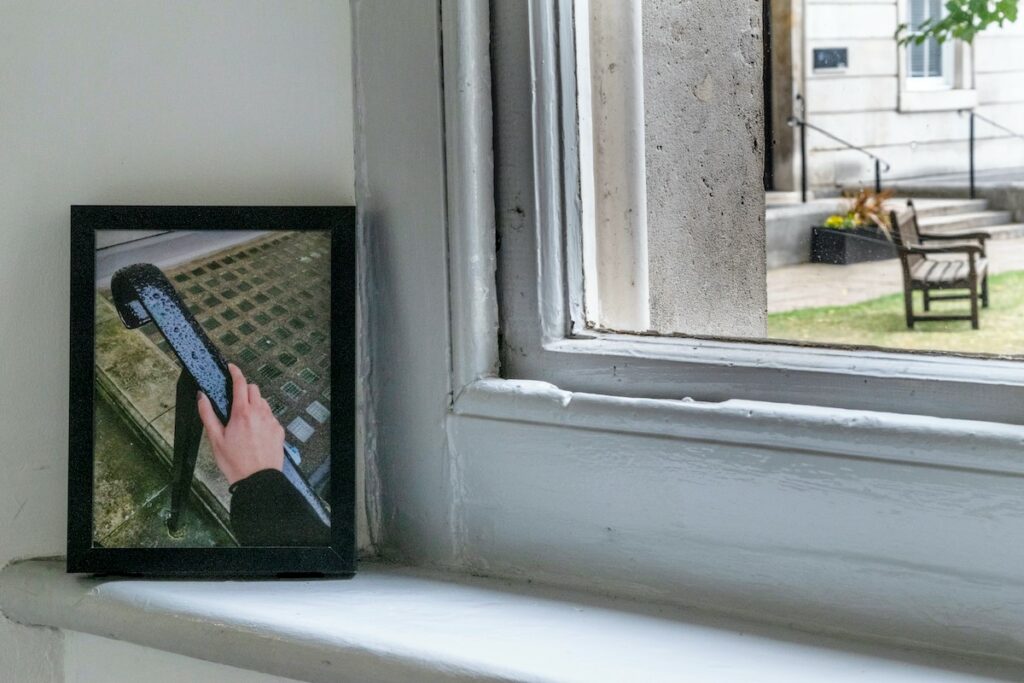A framed photograph on white windowsill of a hand on a handrail