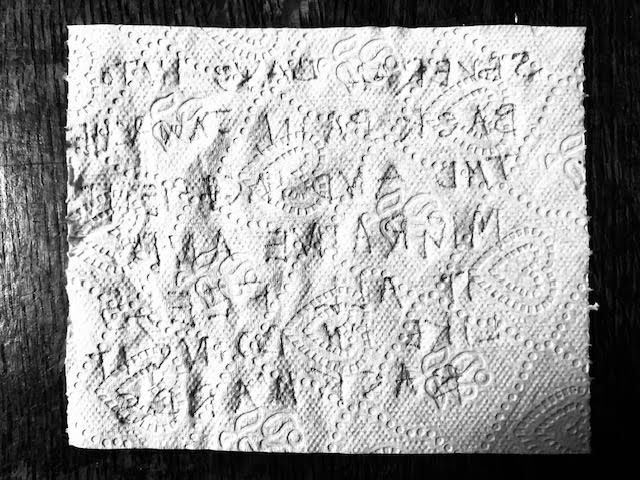 [black and white photo of a sheet of tissue paper with the words ‘Several days into back pain, jaw ache, TMD and incipient migraine and it all feels like i’m doing it backwards’ written in mirror writing in silver pen with some letters the wrong way round and some words misspelled]