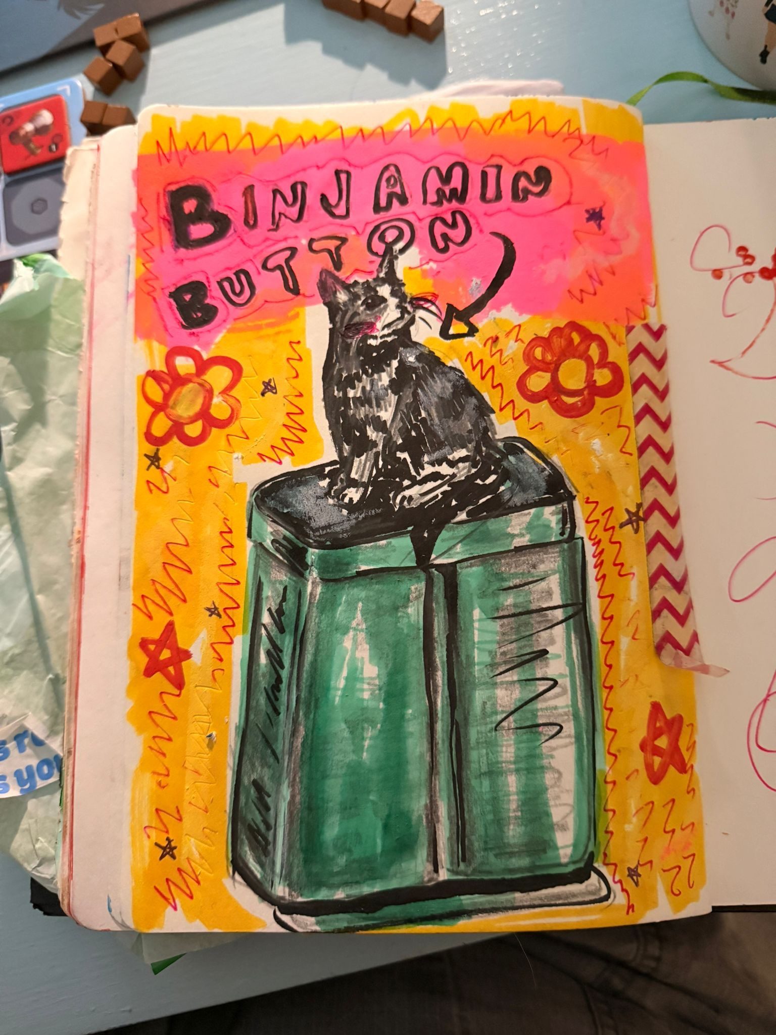 A messy sketchbook page of a cat called binjamin button, because he is sitting on a bin! theres words pointing to him, and hes a black and white cat!