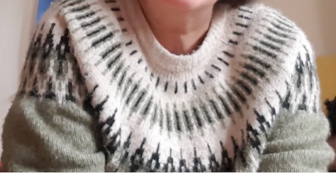 Top of the torso and lower neck of someone wearing a green fairisle jumper