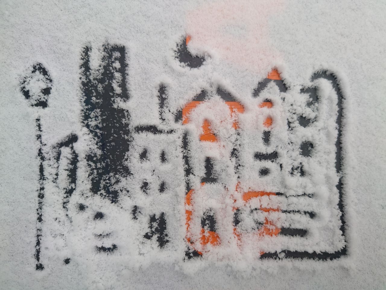 Cityscape drawn in snow on a trash bin lid