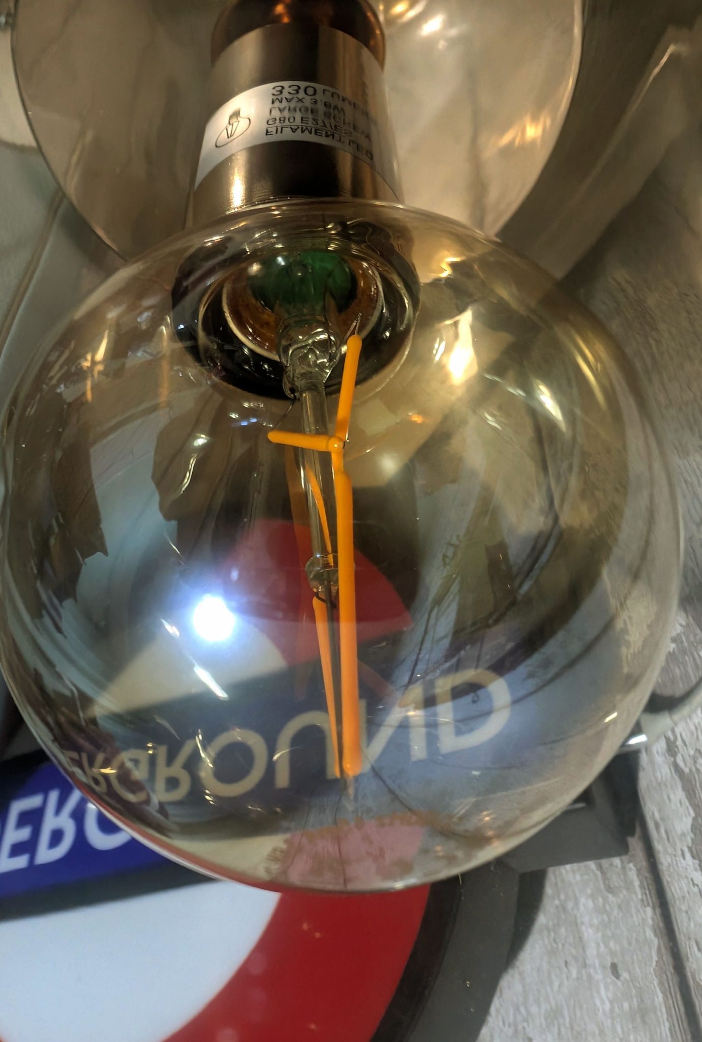 Photograph of a Large lightbulb and London underground sign has been turned upside down and flipped backwards so it is like you are looking from a different angle