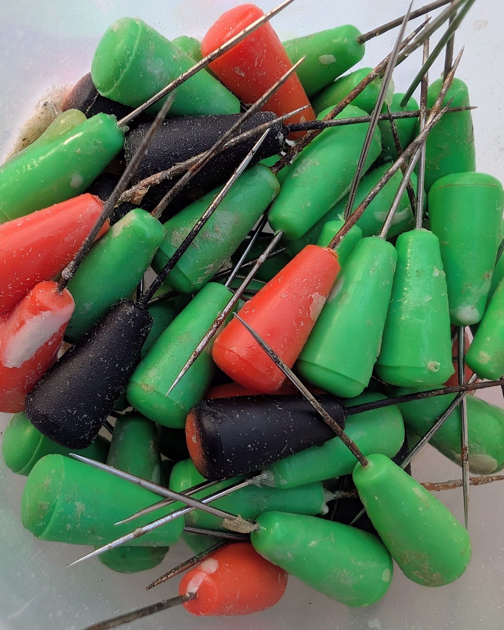 A close up of silver craft pins with orange and green heads