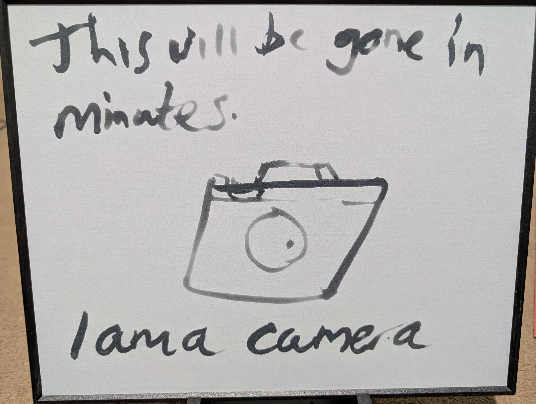 A message and a drawing of a camera on a Buddha board so when the water dries the image vanishes