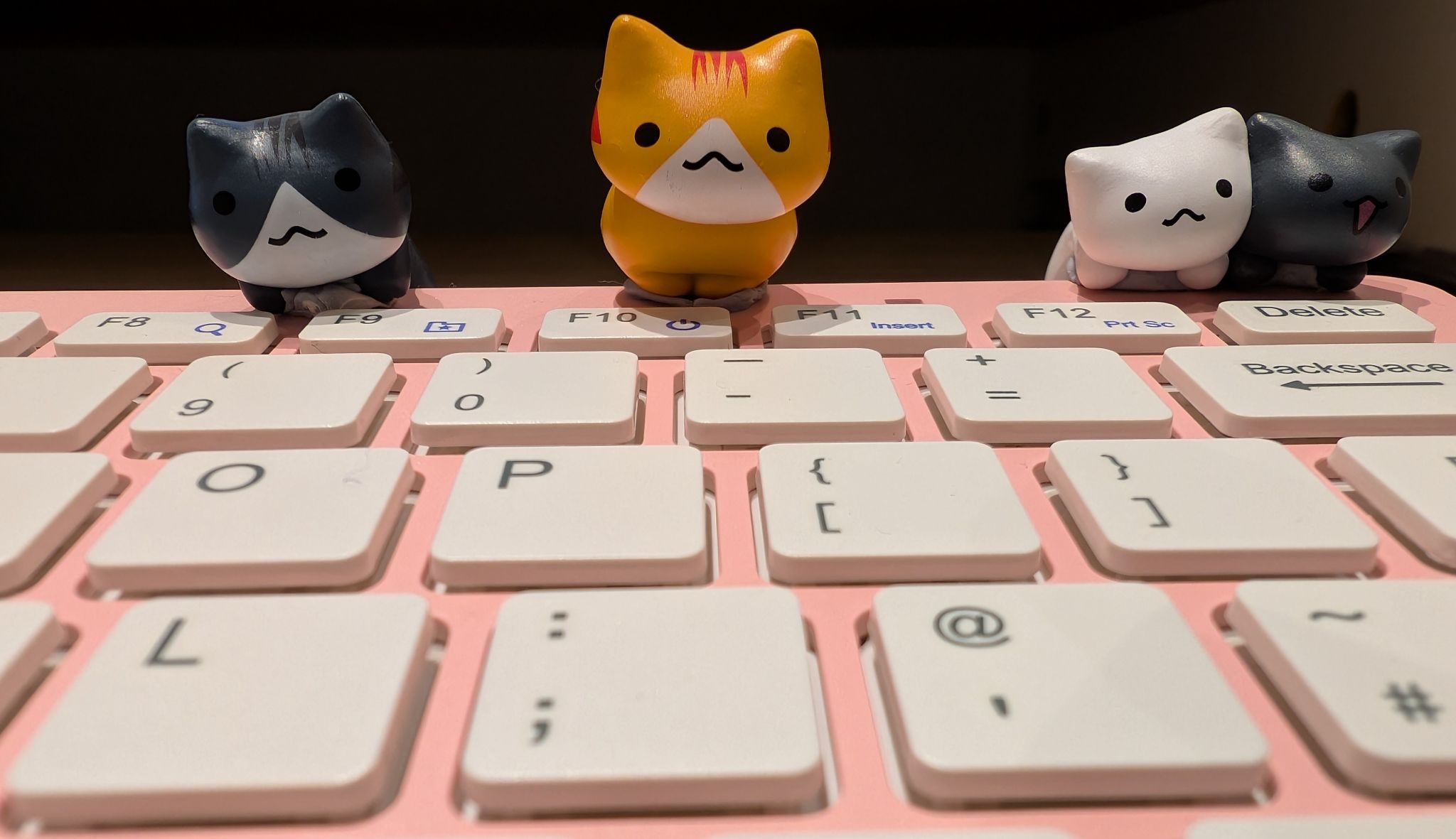 Miniature cat figurines on a keyboard on a desk