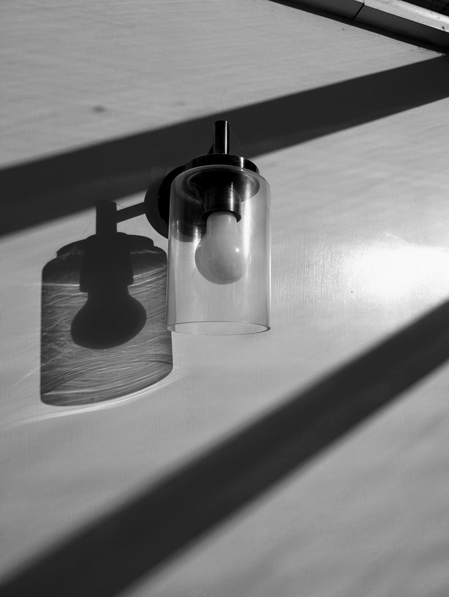 Back and white still life of a wall light and it's shadow