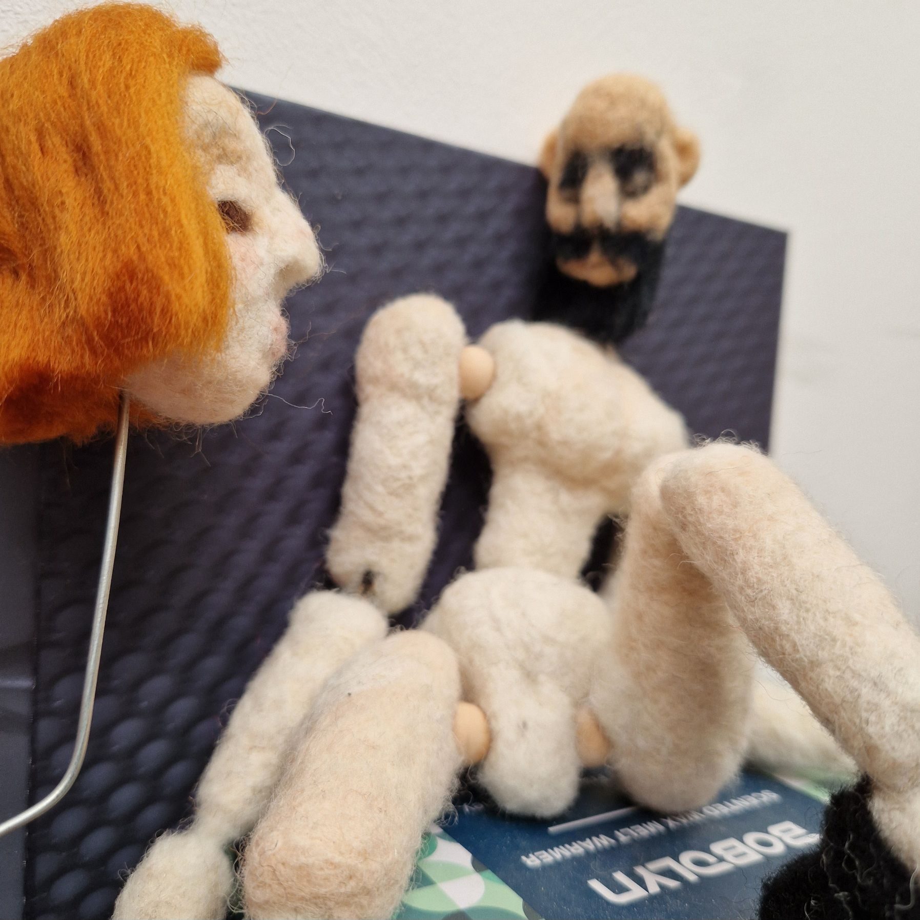 Red headed doll facing doll with female body and bearded man's head