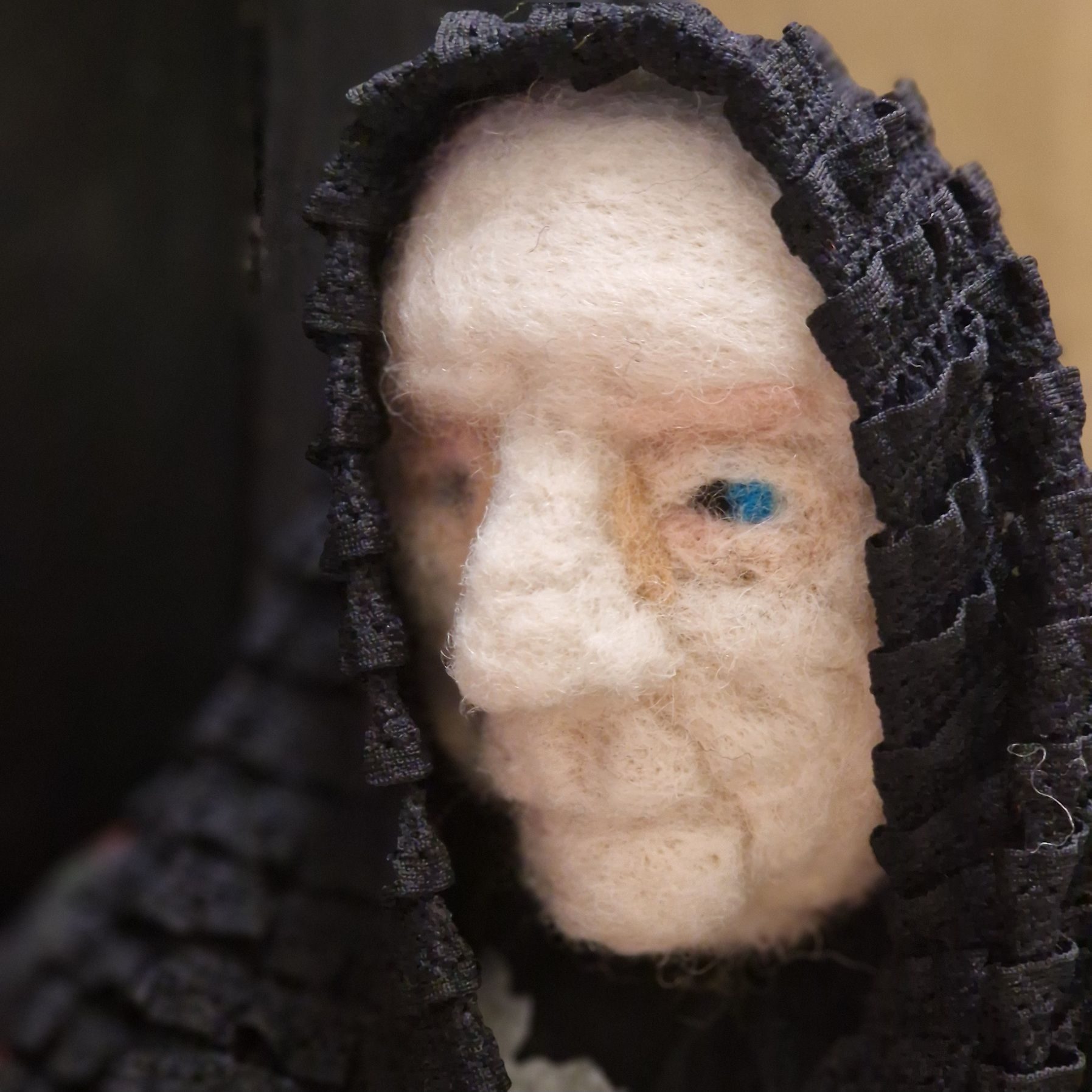 Headshot of a eedle felted old woman wearing a black shawl