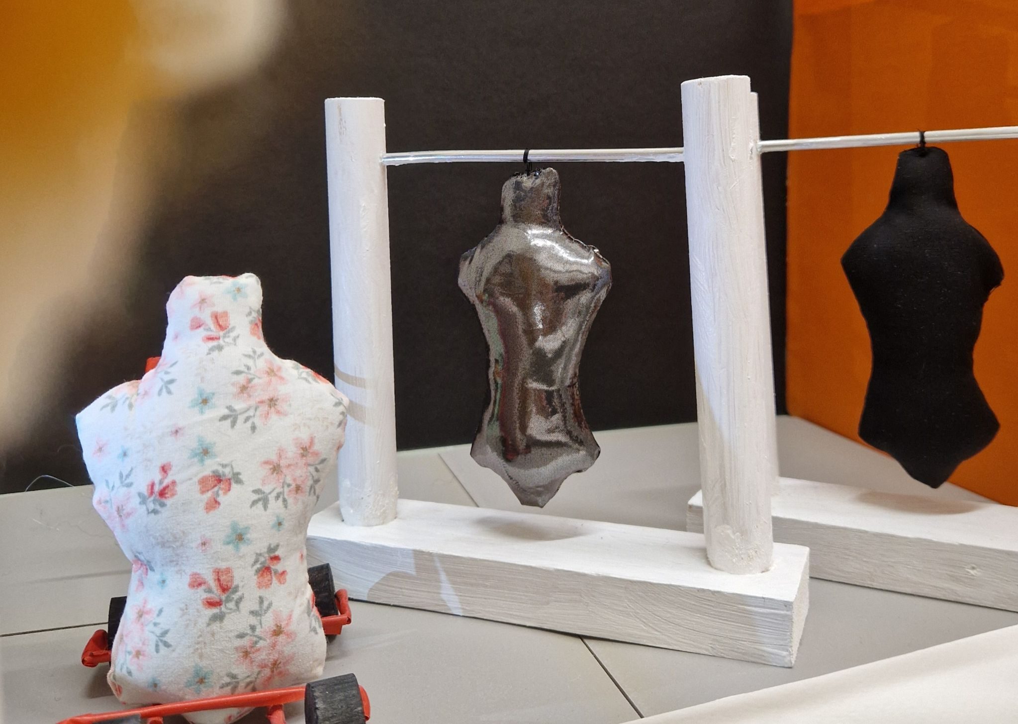 Blurred face of a doll looking into a shop displaying doll bodies hanging from racks