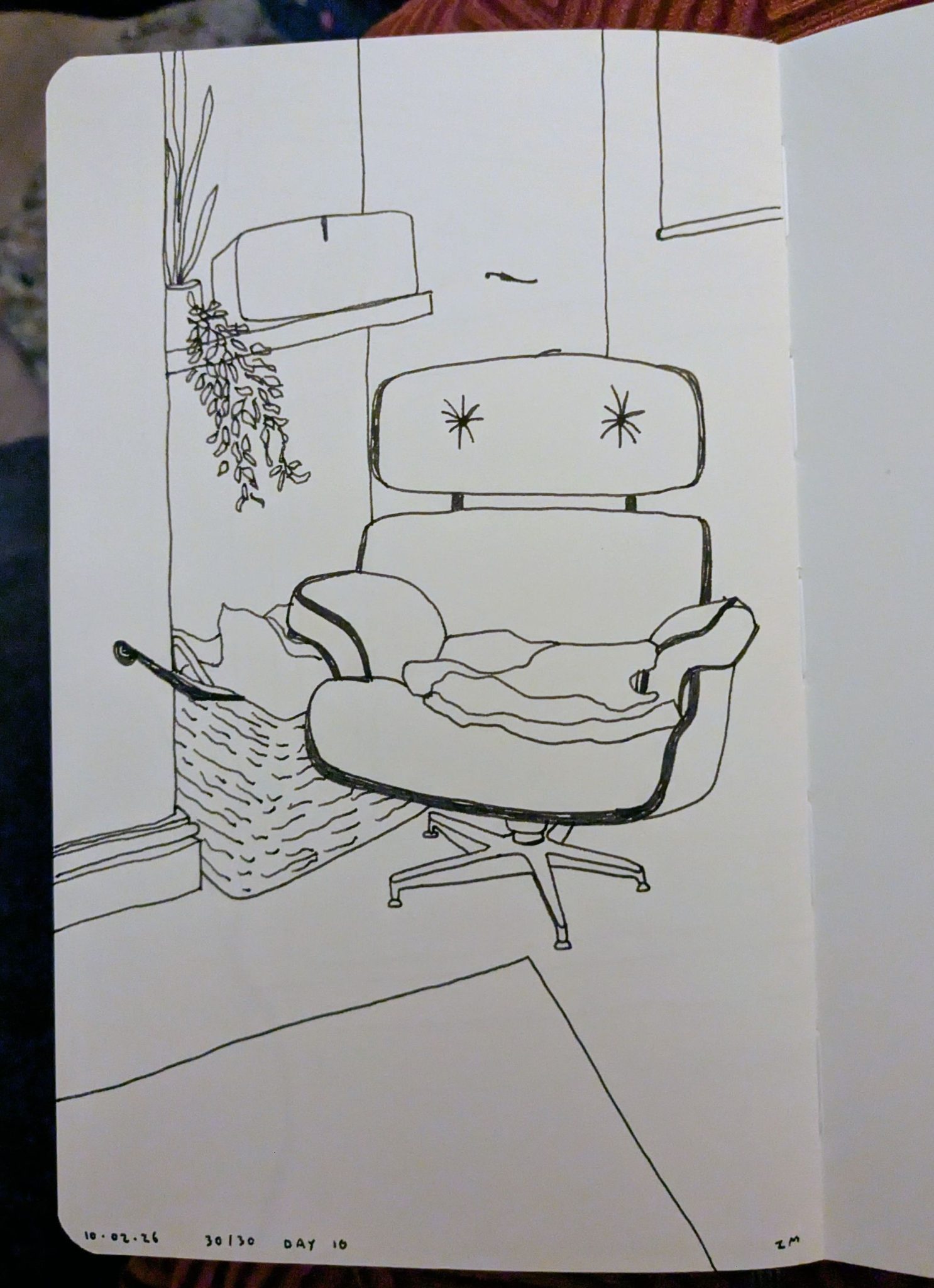 Photograph of a sketchbook page showing a pen drawing of a chair in a corner