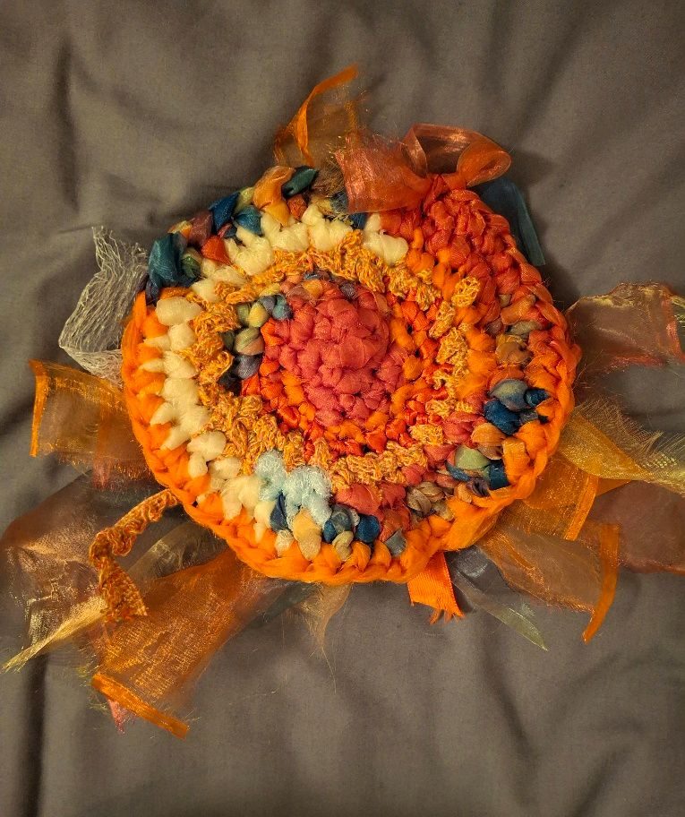 Large crochet circle comprised of lots of different fabric scraps in different colours