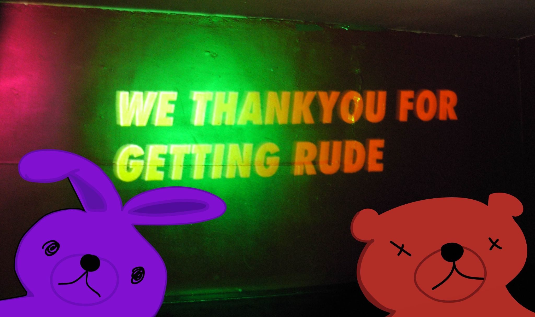 A photograph of a sign reading We thank you for getting rude, with a digital drawing of purple cartoon style bunny on the left and of red cartoon style bear on the right
