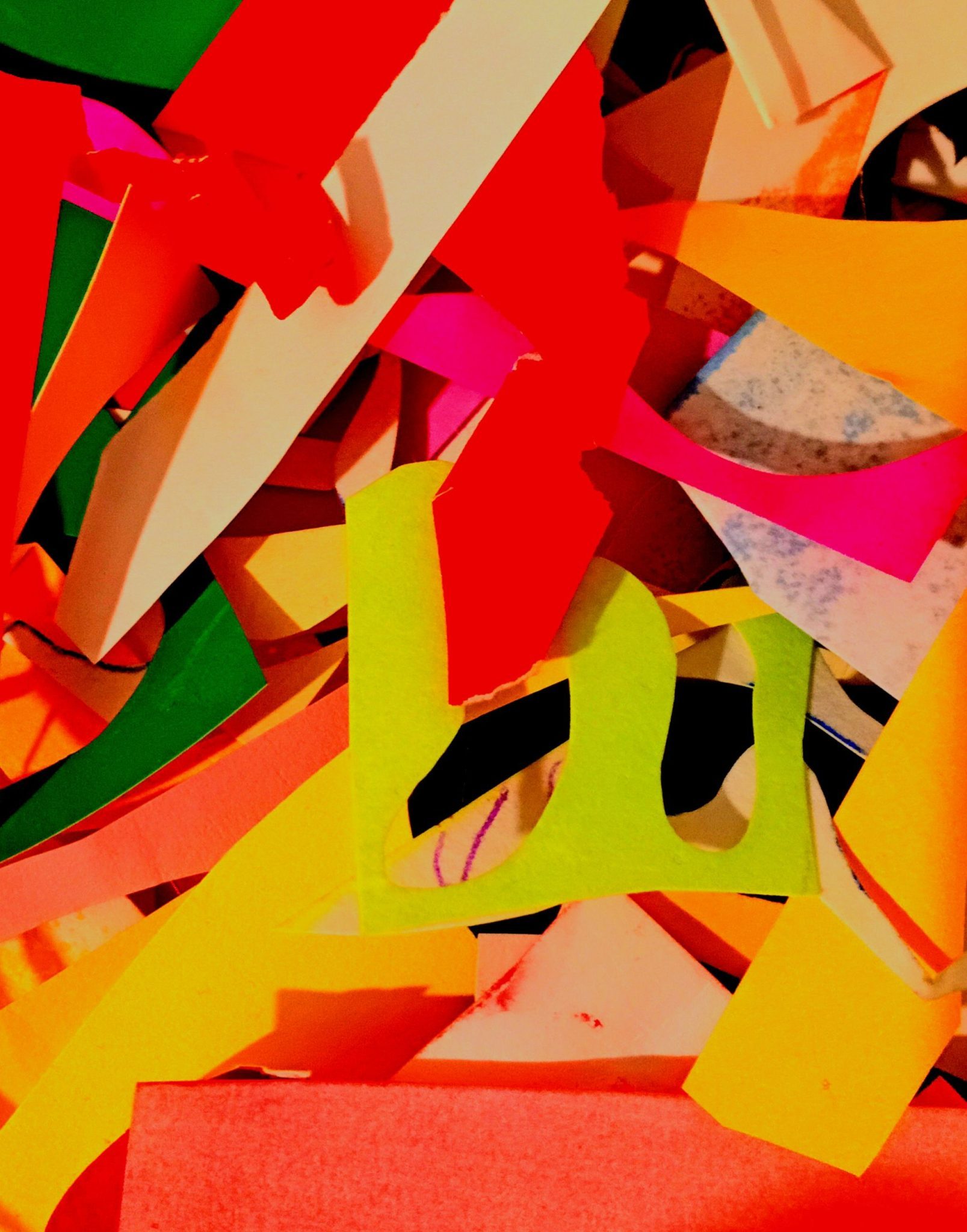 Random paper cutouts,  mainly red, yellow and pink and some green pieces