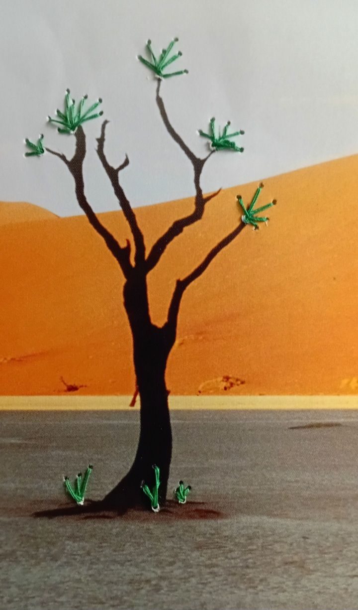 A bare tree with dark bark, set in a desert with orange sand dunes. Green stitches replicate the leaves.