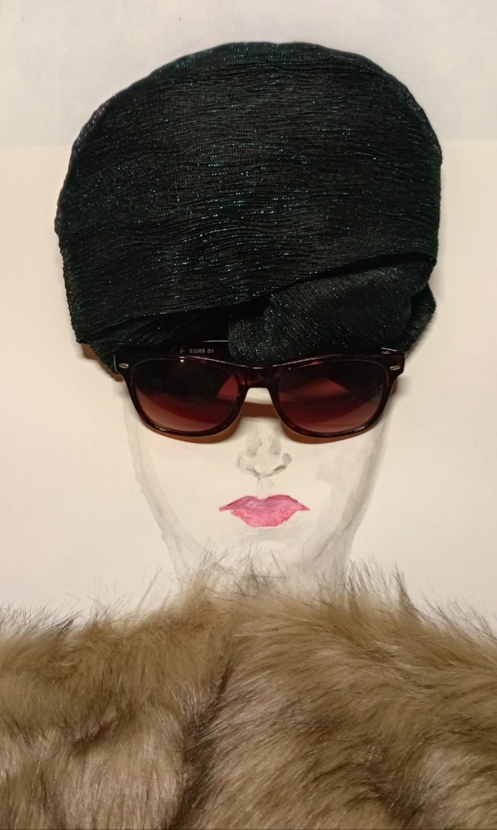 A drawing of a woman's face. Placed on top of the drawing to complete image is a pair of sunglasses, a fur stole and a dark green head wrap.
