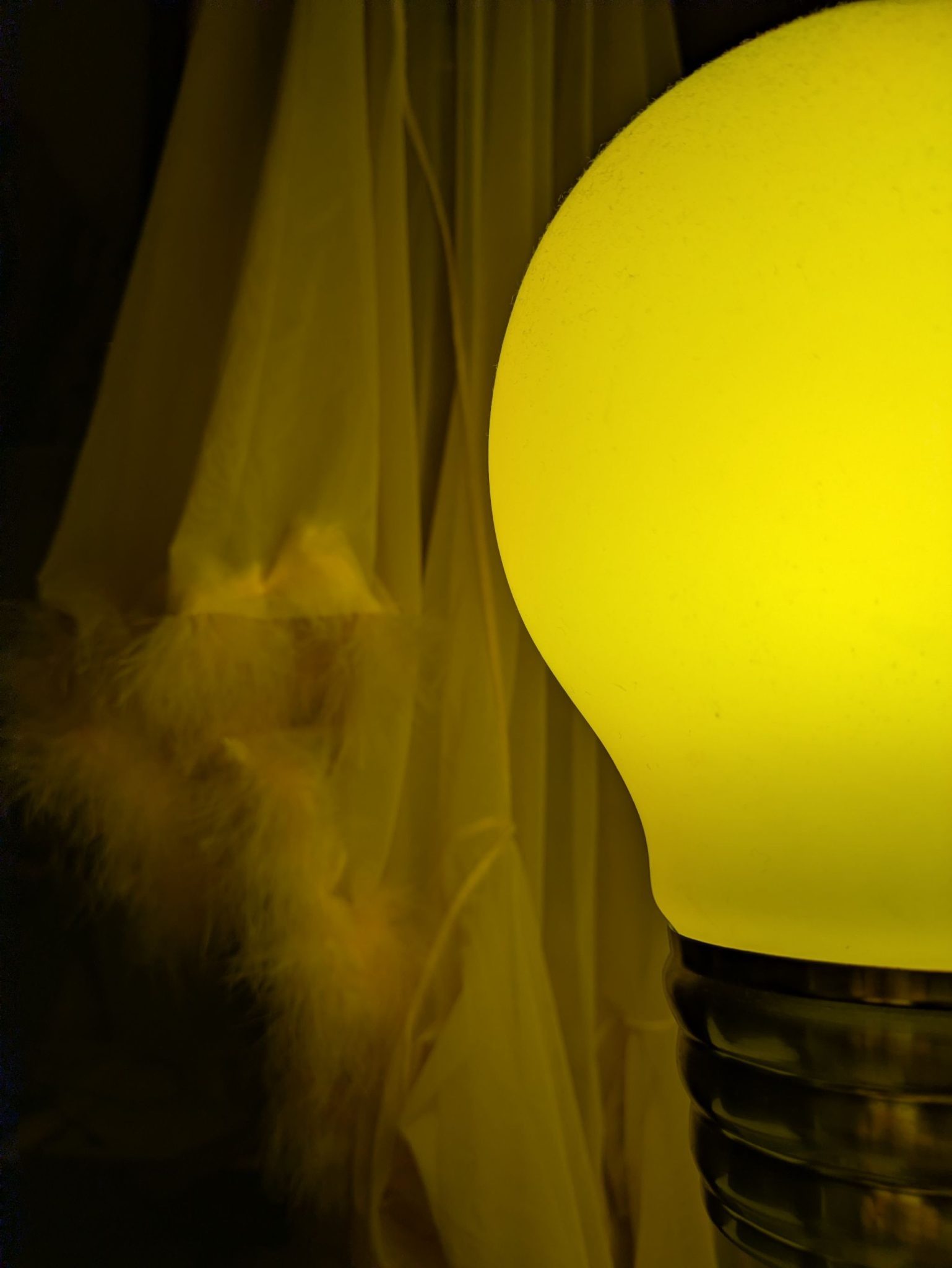 Fluffy pink rubber in background and warm glowing large lightbulb lamp in foreground