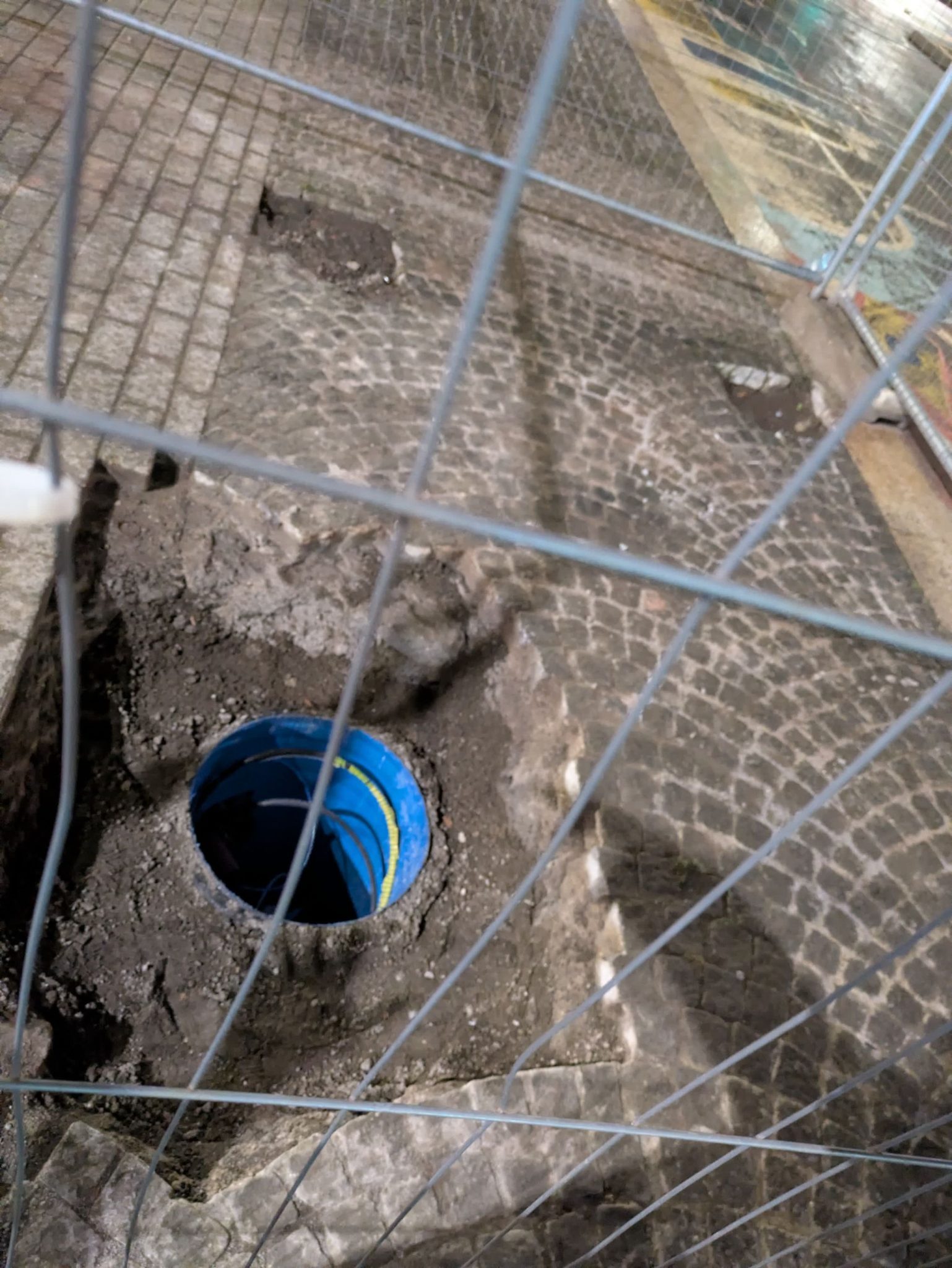Picture of shadows extending hands into a hole in the pavement