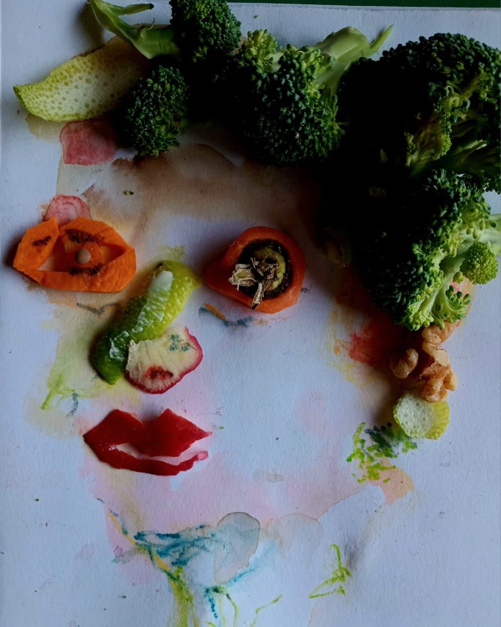 Portrait with washes of watercolour, pieces of broccoli,  apple, carrot, lemon peel
