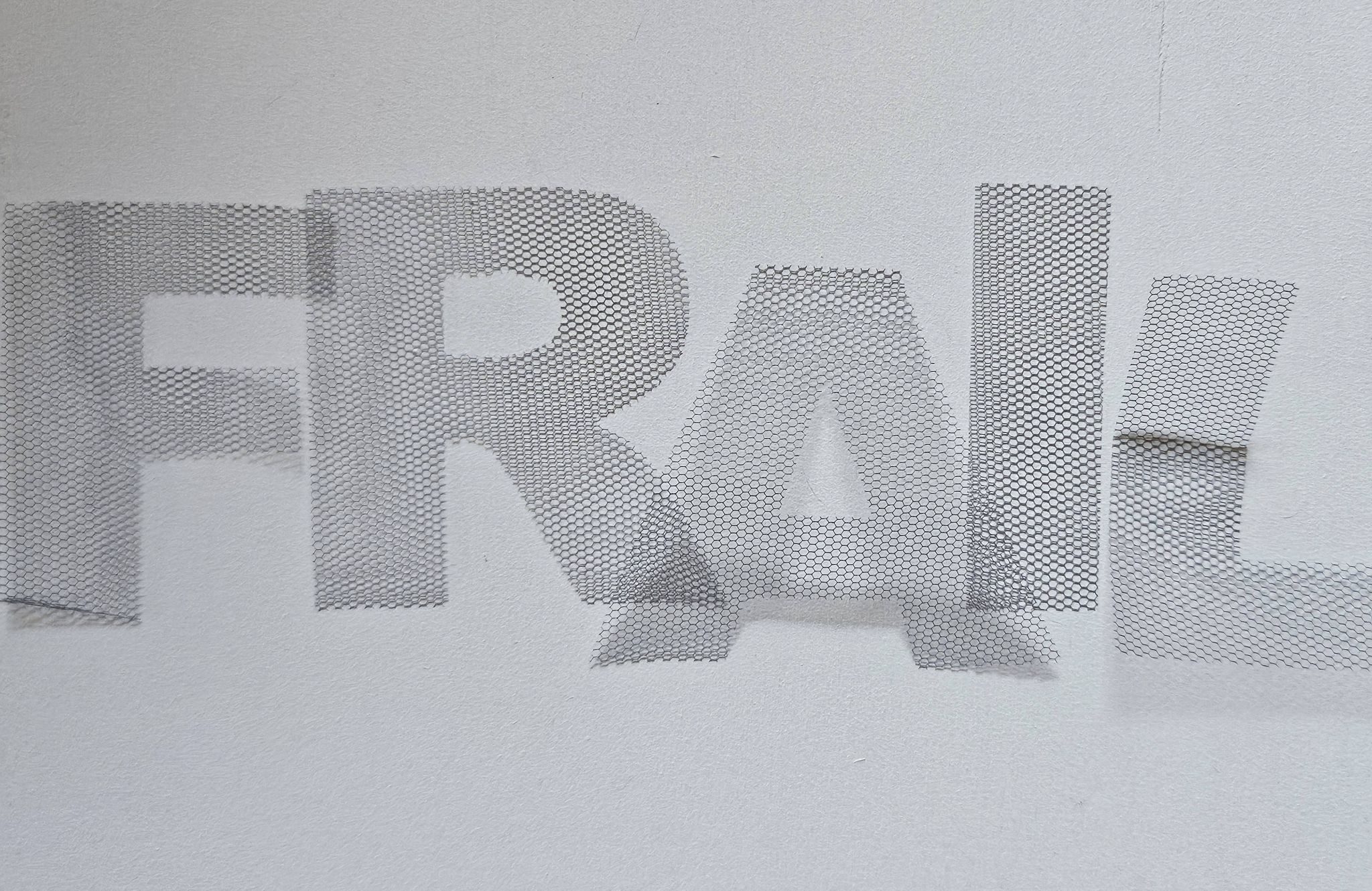 Delicate textile letters overlaid to spell the word Frail.