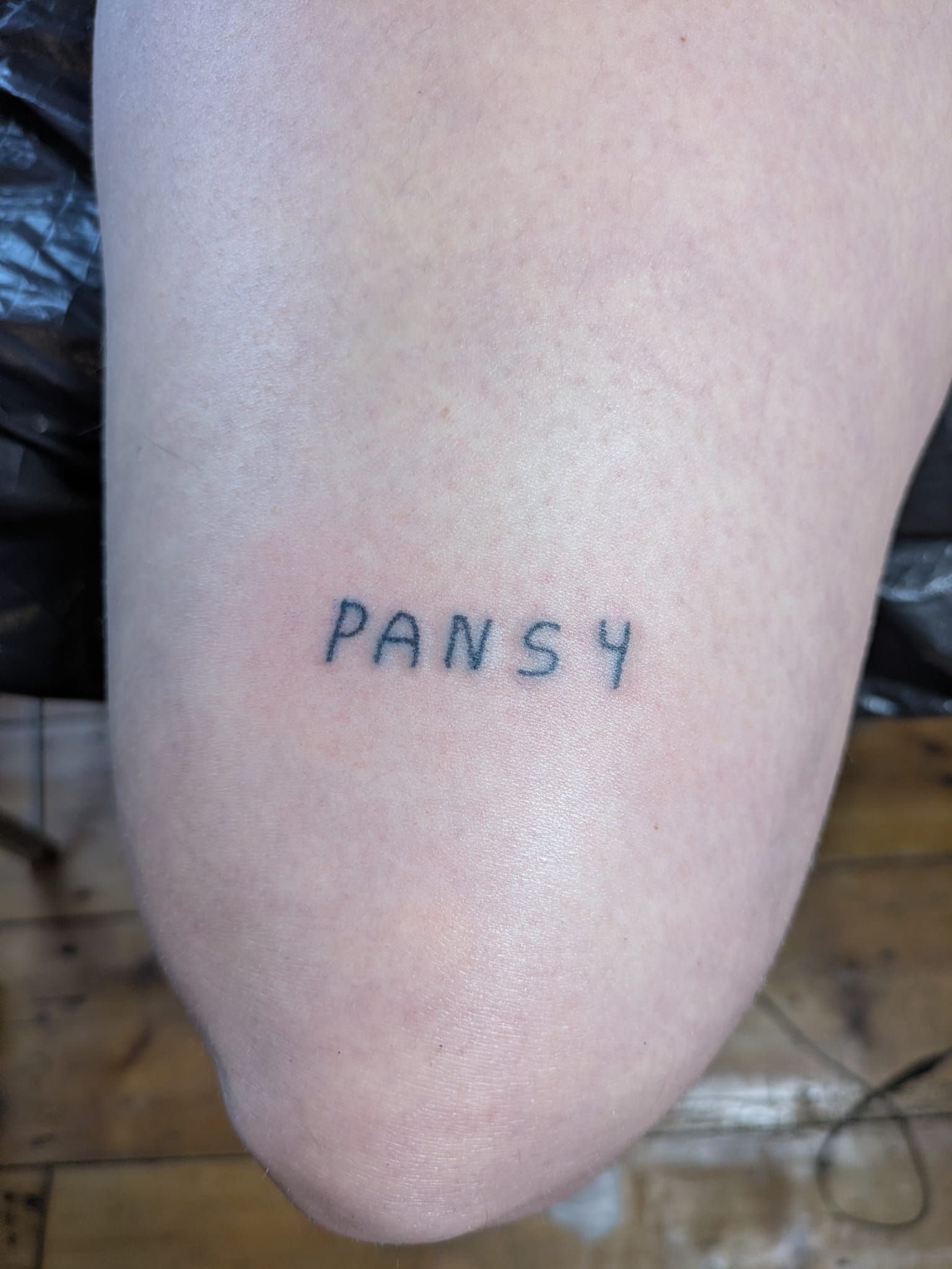 Photo of a stick and poke tattoo reading pansy
