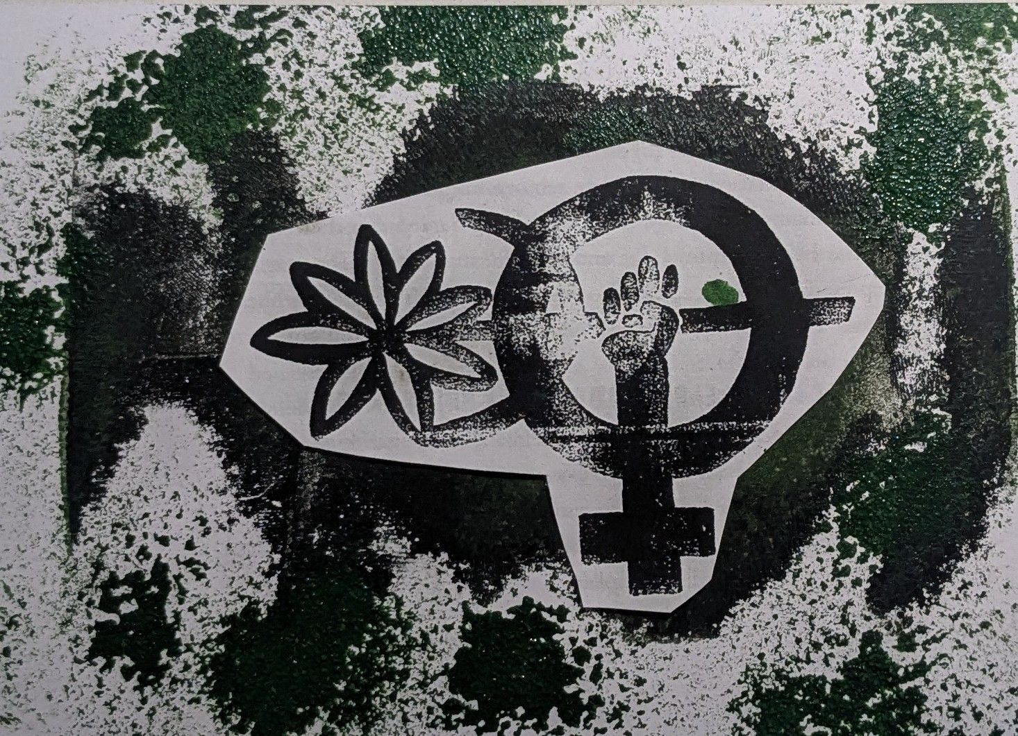 A green and black splotched background with a symbol cut out and stuck in the middle. It is a female symbol with a hand holding a flower in the middle