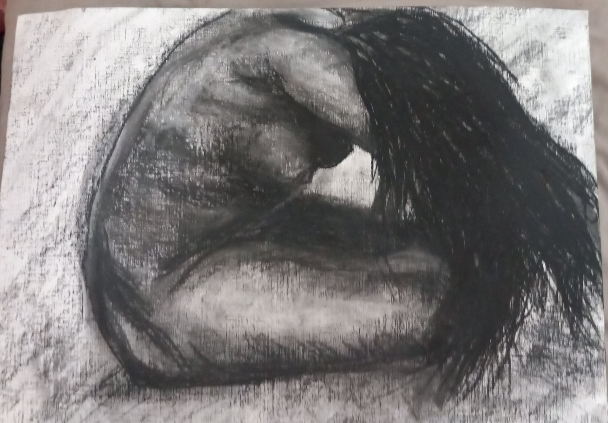 woman with hair thrown forward, side facing bent over cant see face, dark with faint highlights on leg and arm, back. distorted background made with charcoal used on  side, charcoal and black n whire pastel