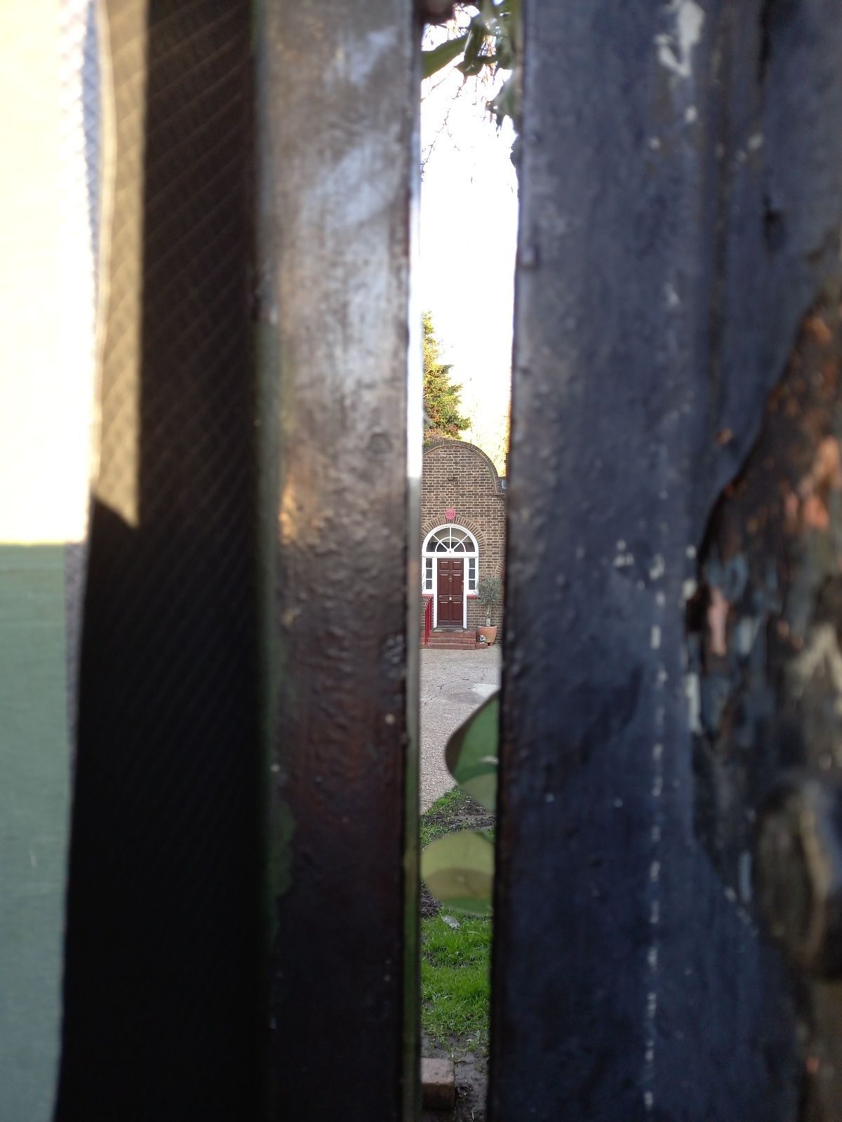 Taskmaster house glimpsed through fence