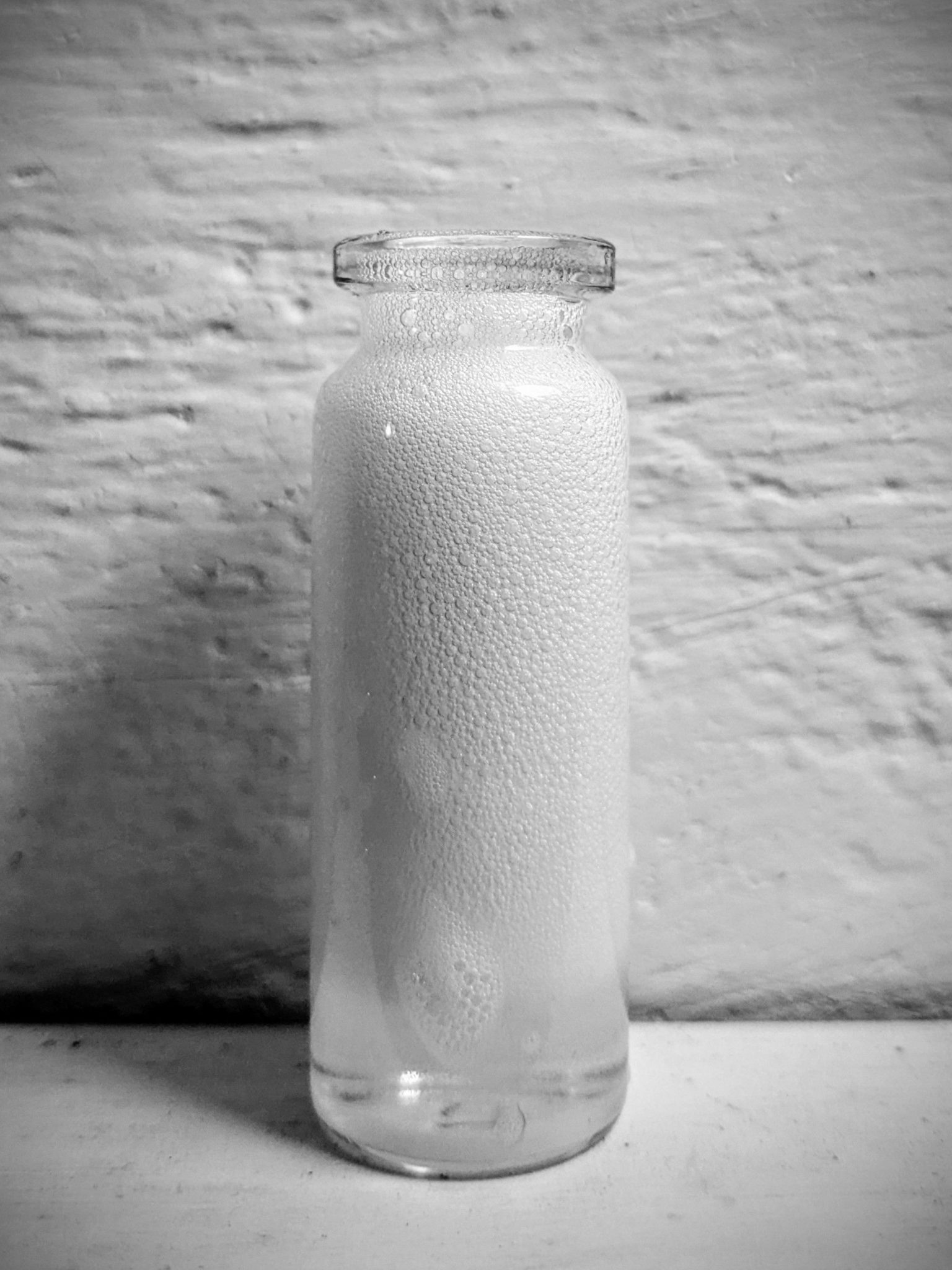 A small glass bottle filled with bubbles from washing up liquid