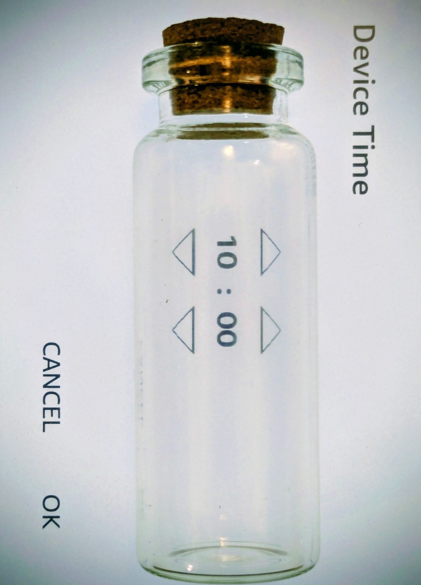 A small glass bottle against a screen backdrop that says Device time and Cancel OK; through the bottle a digital displays a clock marked 10:00