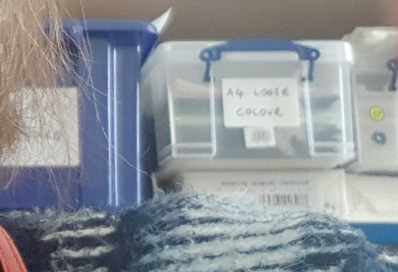 detail of fairisle jumper in front of plastic box labelled loose leaf folders