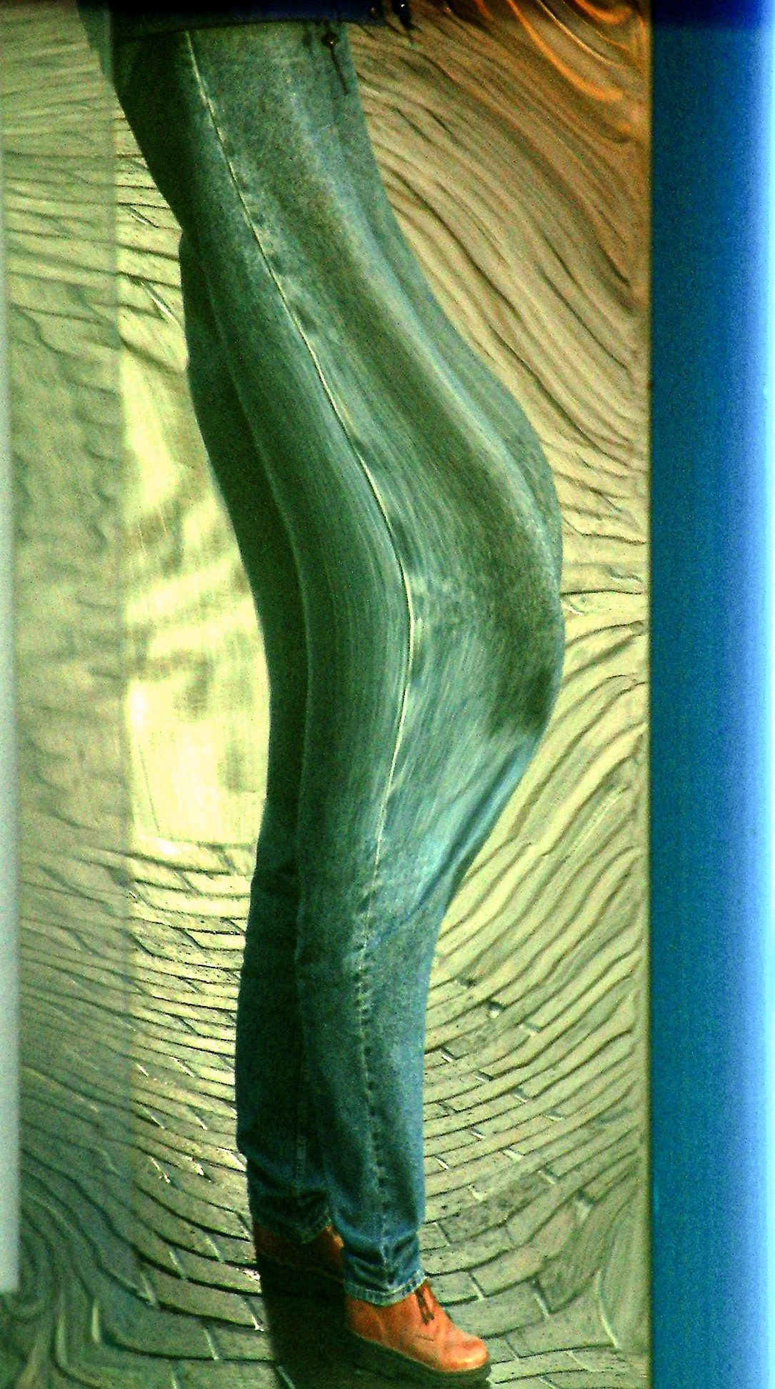 Photograph of man's denim covered leg distorted in a hall of mirrors