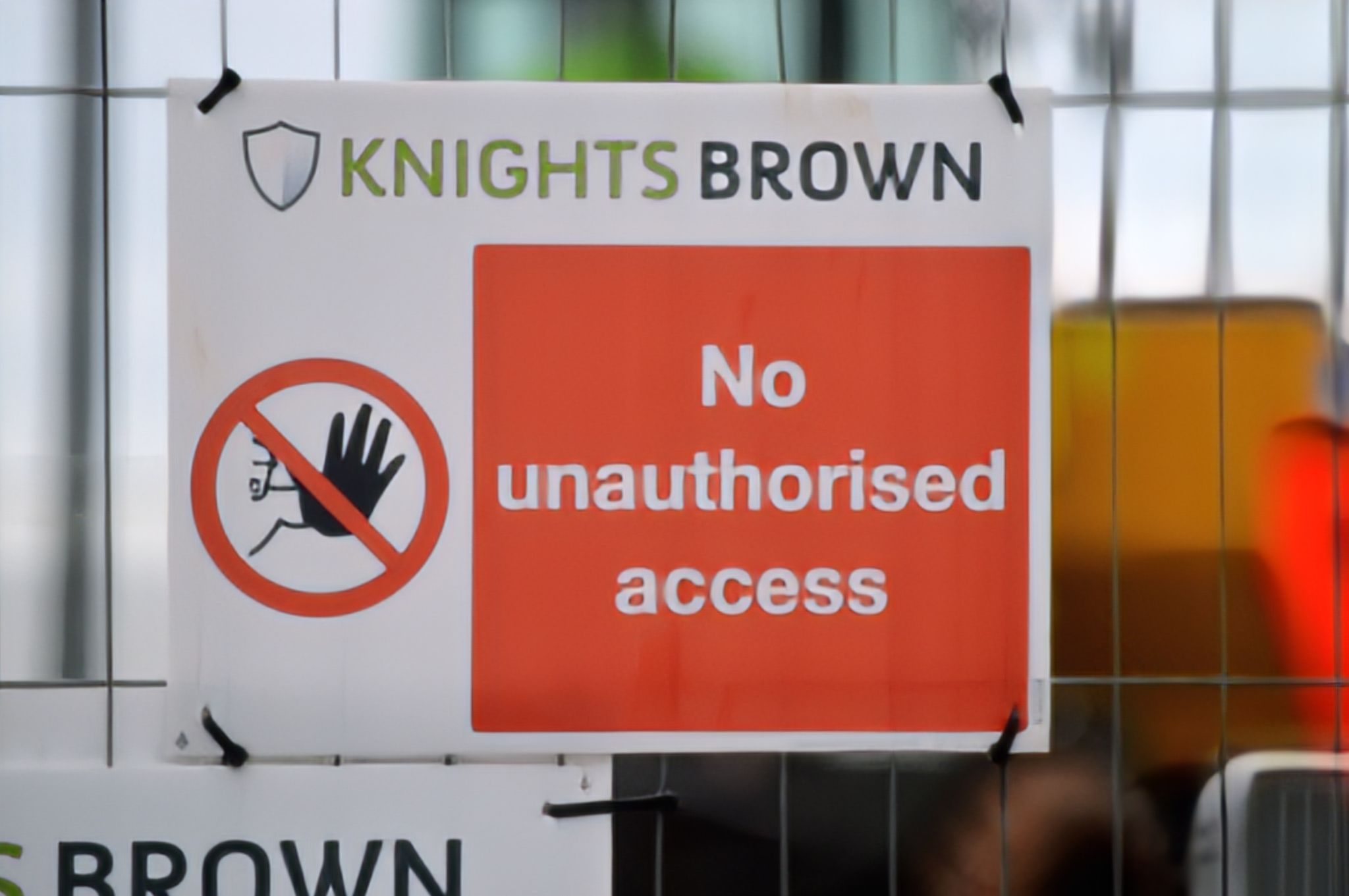 Temporary sign attached to a temporary fence. Sign reading no unauthorised access. White writing on a read background.