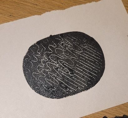 An ovall black ink monoprint with various expressive lines and marks.