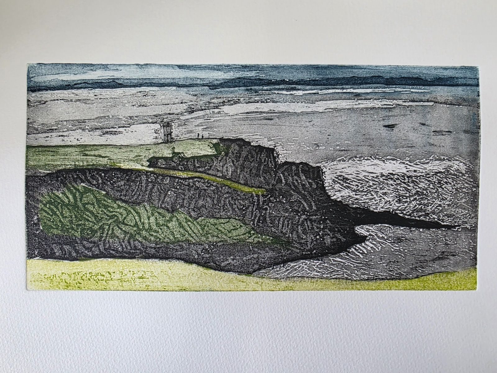 A rocky headland in the sea. The light is striking the sea and the heafland. On top of the hsadland is a small light tower. There are some people on the headland. Work is mainly black and greens