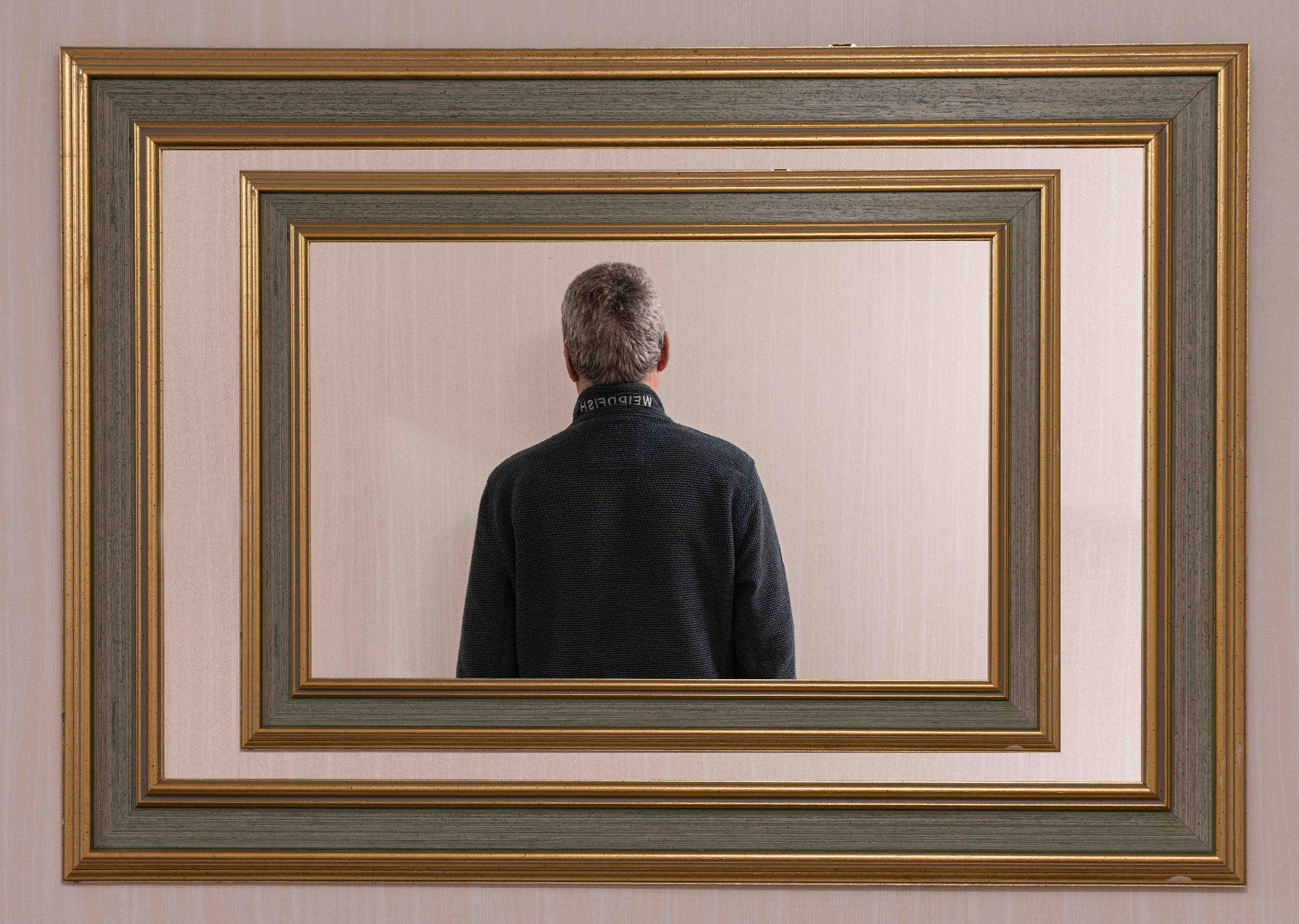 The reflection of a mirror containing the reflection of the back of a man.