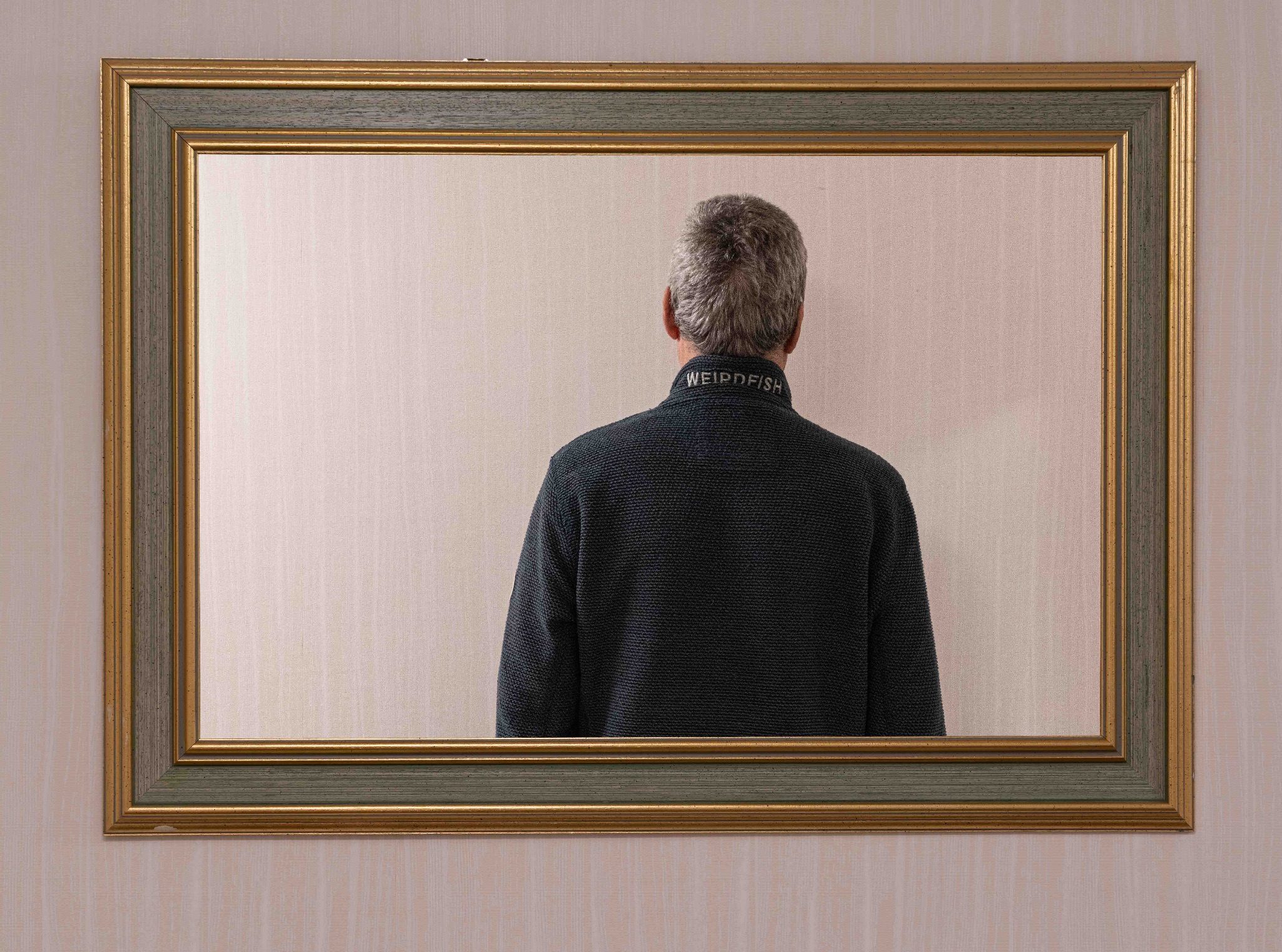 A photograph of a mirror where only the subject's back can be seen and no camera is reflected in the mirror