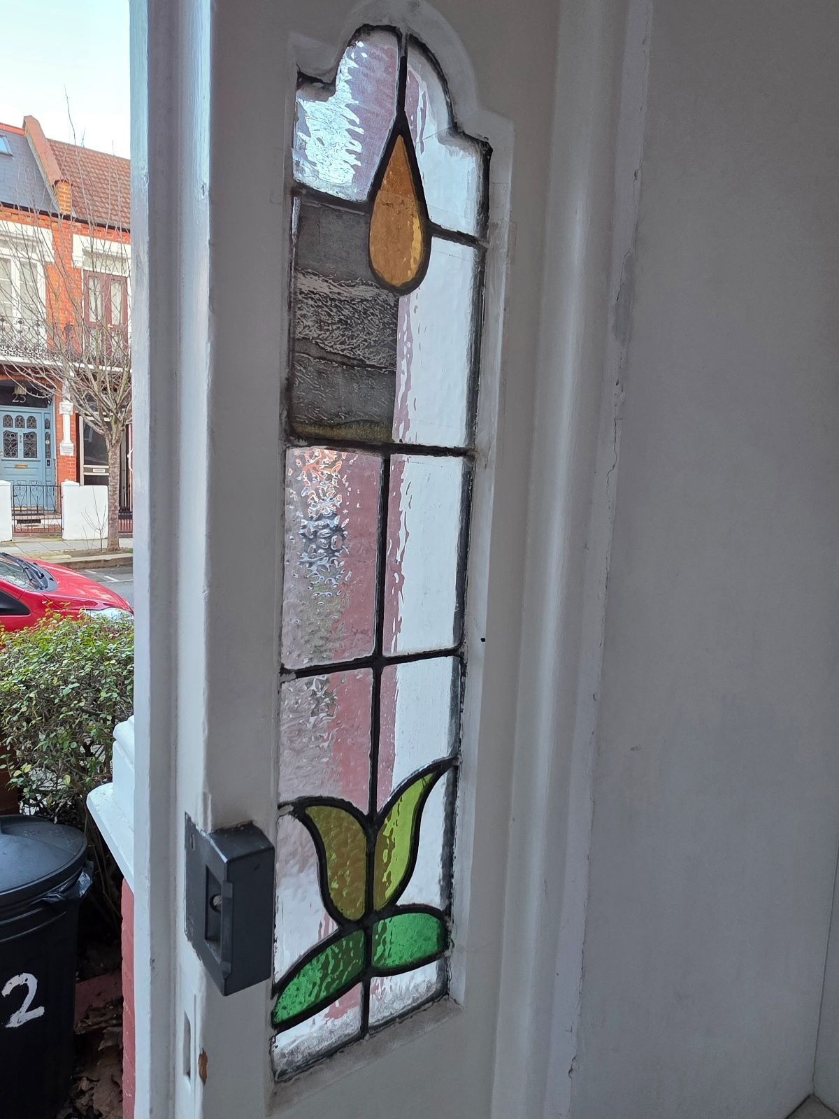 Stained glasd in a door with one pane replaced by artwork on paper