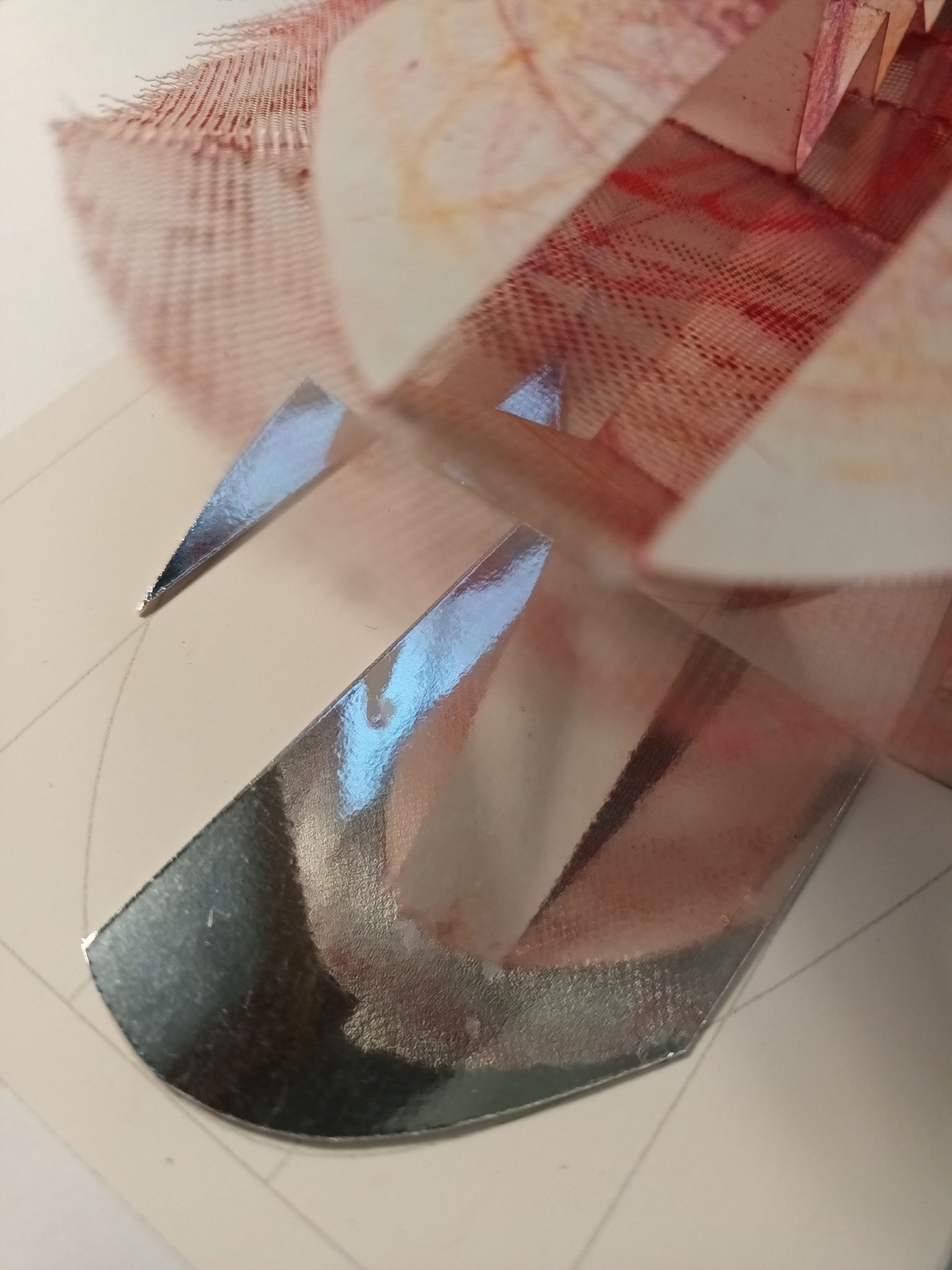 Detail of a small abstract artwork made from paper, gauze and mirror.