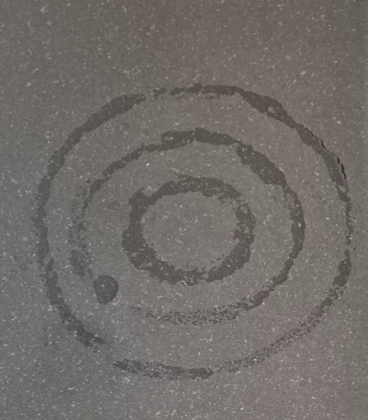 A fragile spiral of water briefly claims space on stone, destined to evaporate like a thought at dusk.