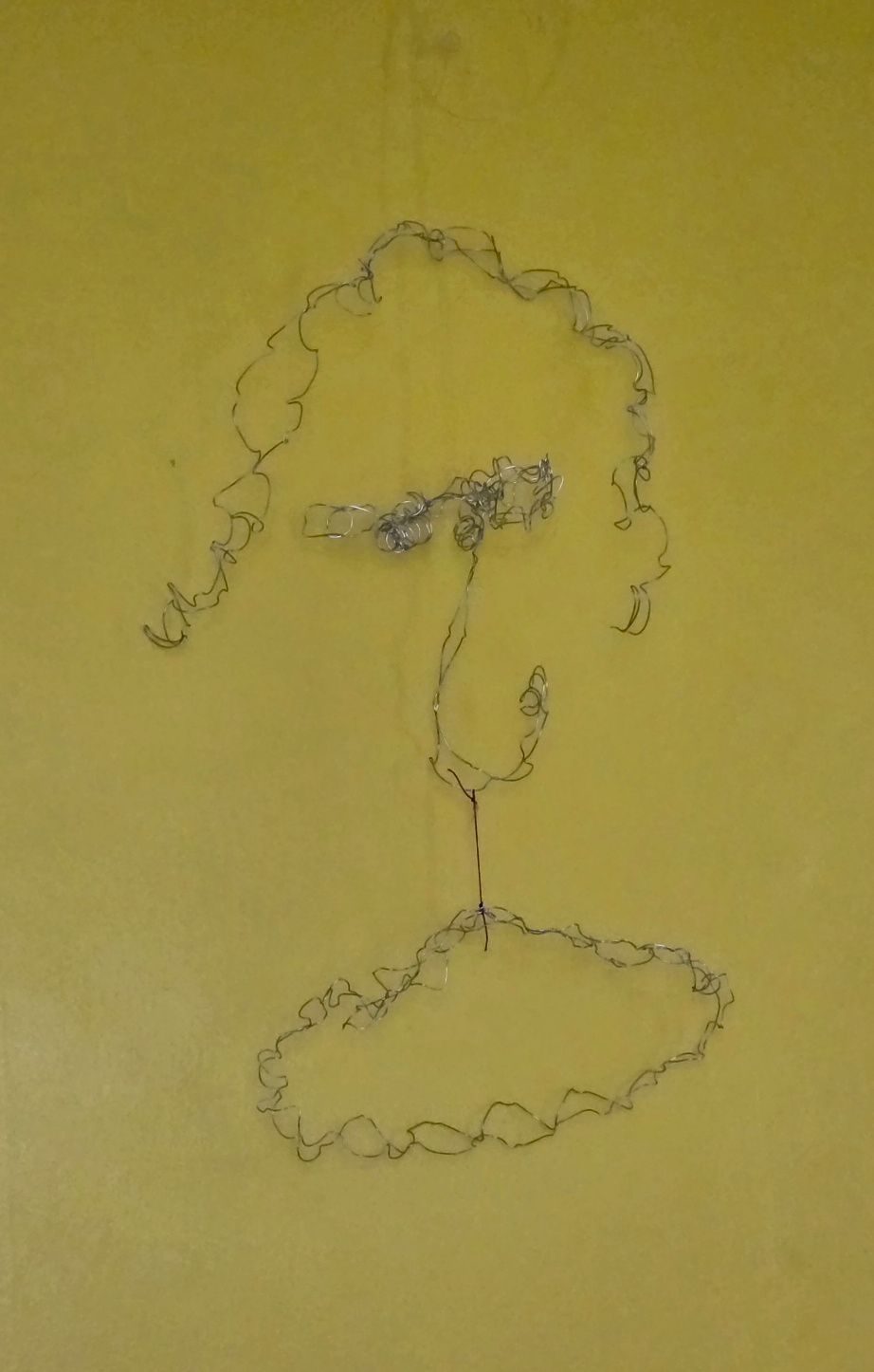 A mobile made up of metal wire depictibg a face