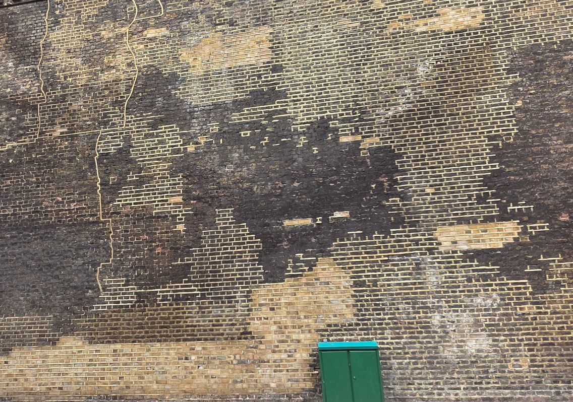 A brick wall which has been repointed. In front of it is a green box