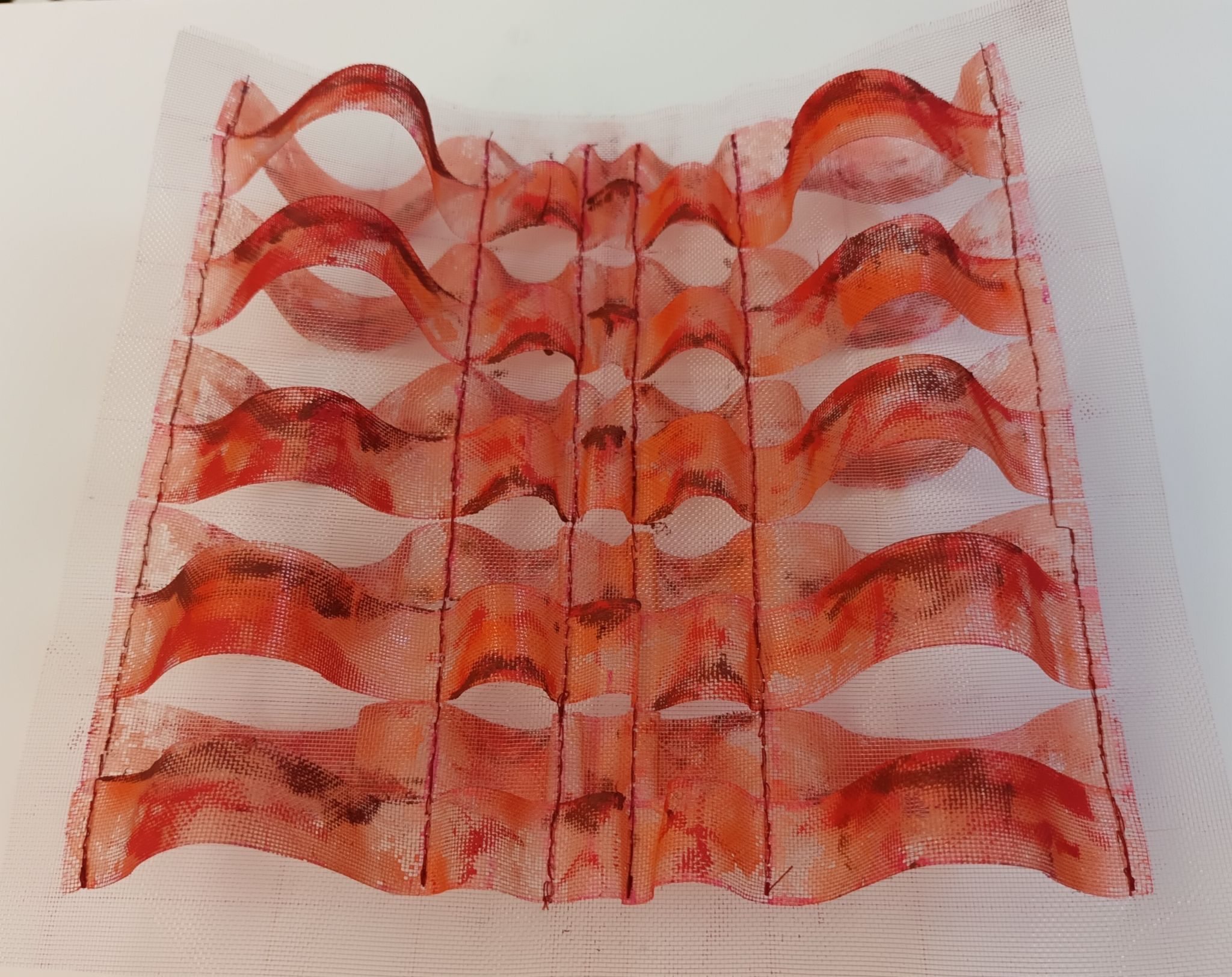 Undulating strips of gauze stitched into columns - colour is sgmhades of orange