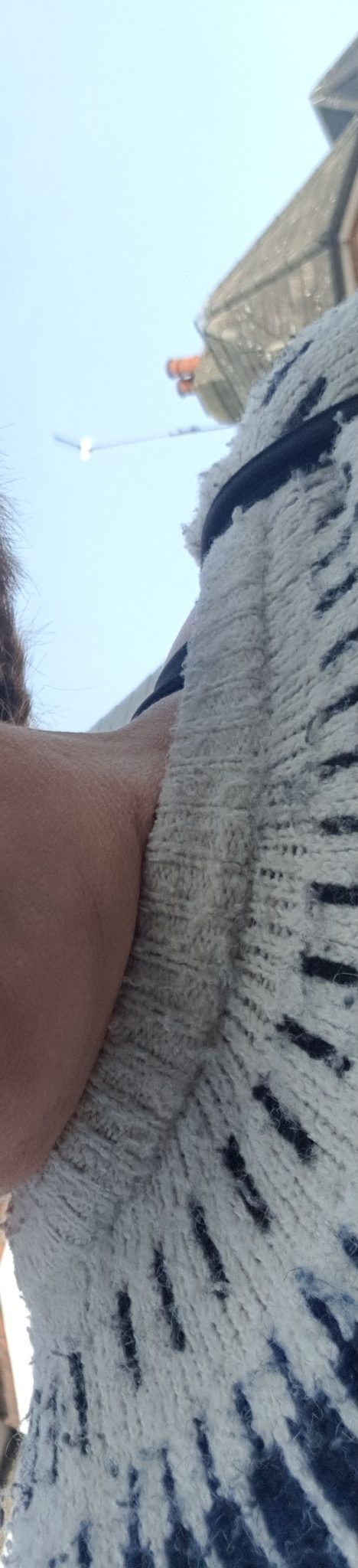 detail of fairisle jumper and neck, glimpse of urban environment