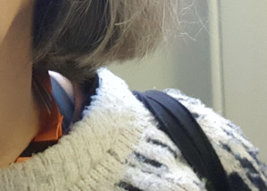 detail of fairisle jumper, face, hair, lanyard and buildings