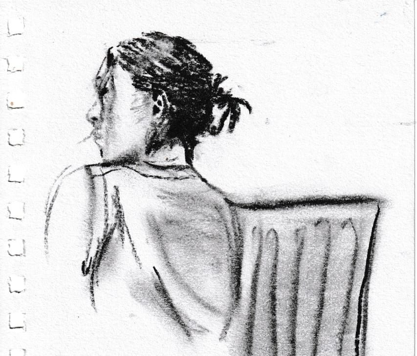 Charcoal portrait of a person faced away, sat by a radiator. Their hair is up in a clasp.